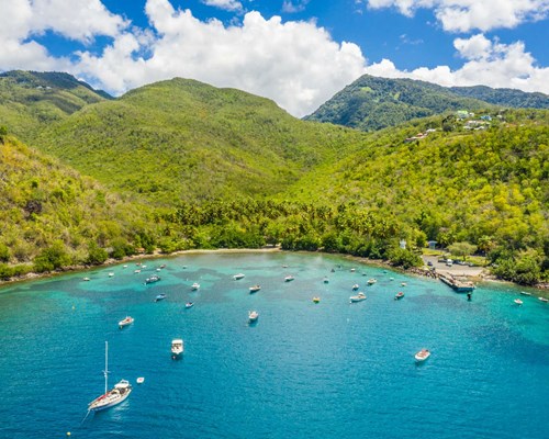 Aerial view of yachts docked up in tropical beach cove with bright blue waters