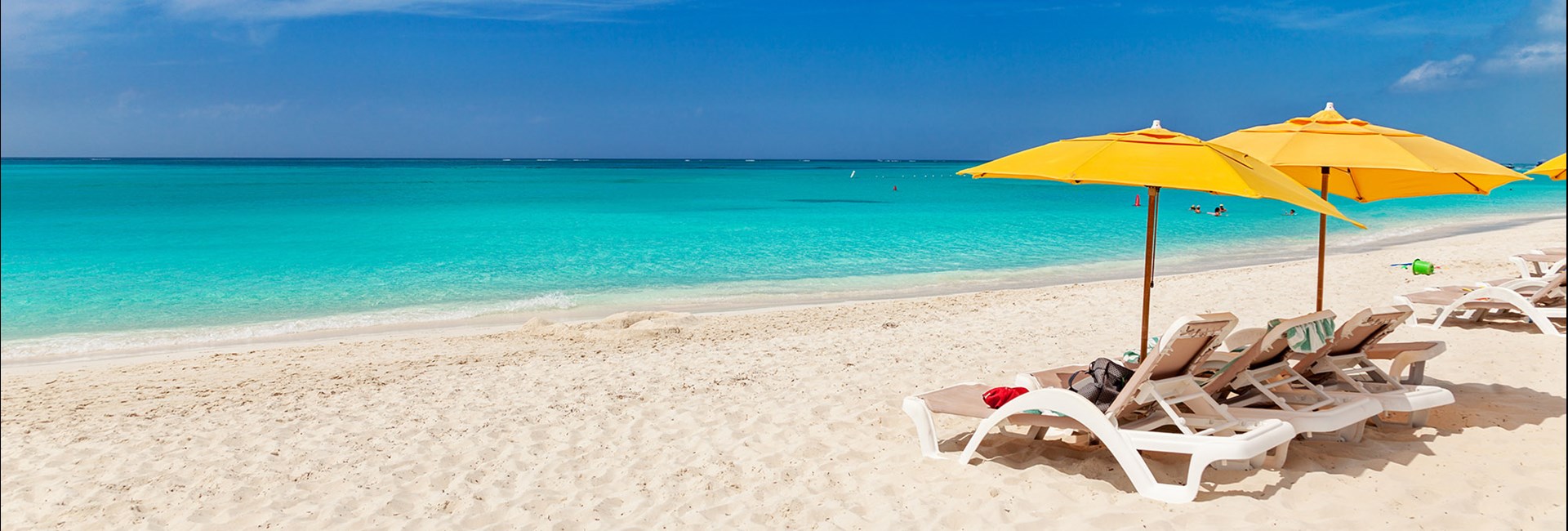 White sun loungers and yellow umbrellas lined up on a white sand beach o