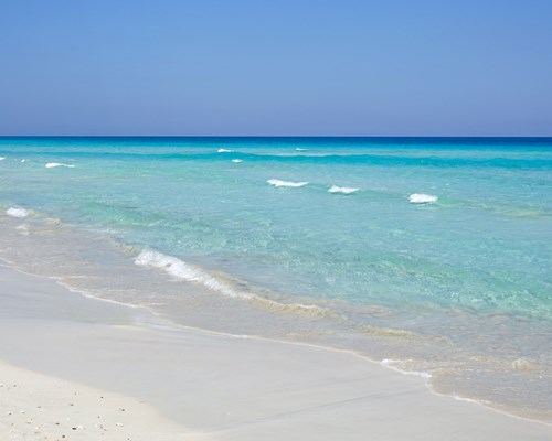 Small clear blue waves crashing on a white sand beach