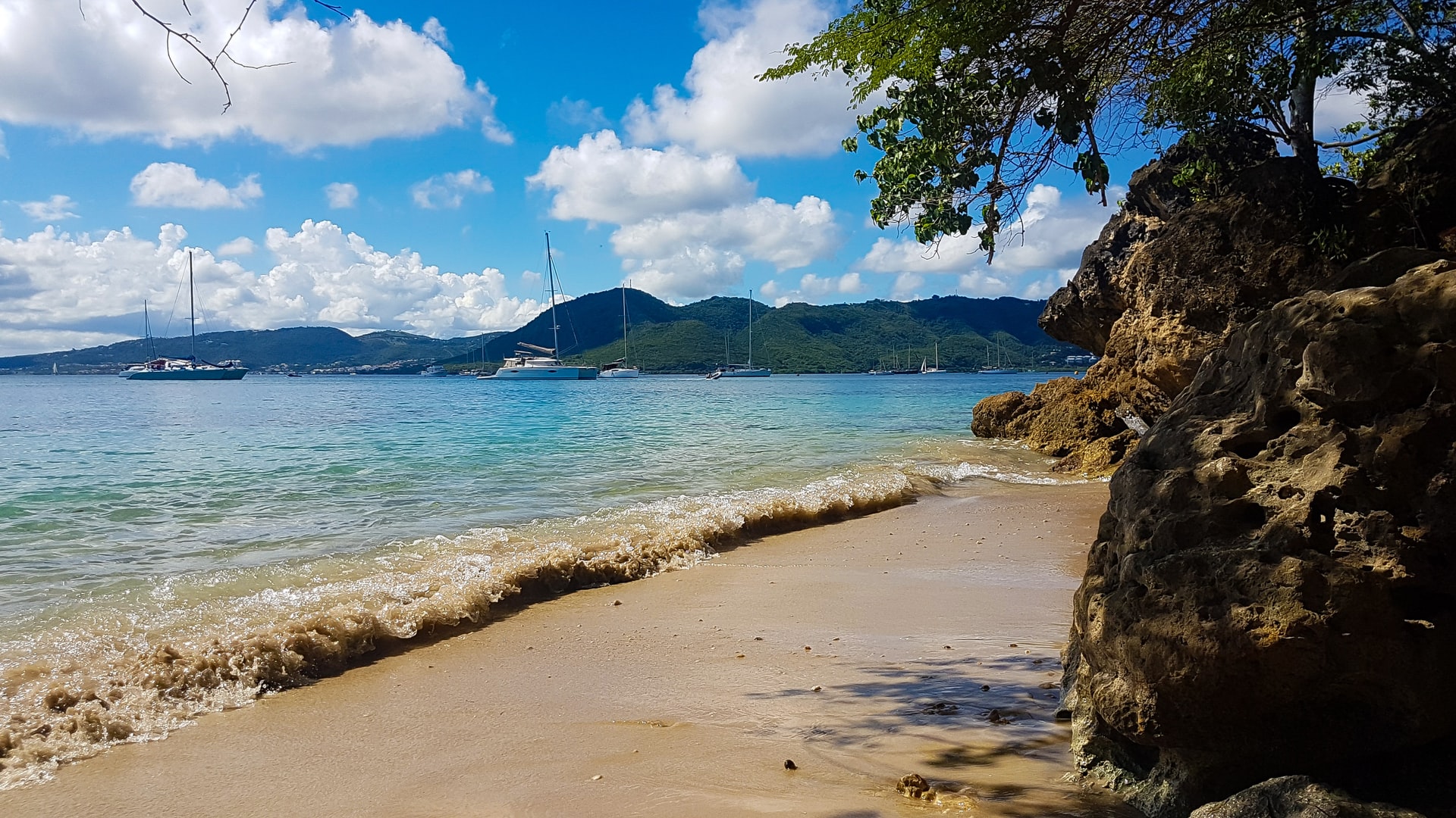  Yachts docked in a small dark-sanded tropical beach