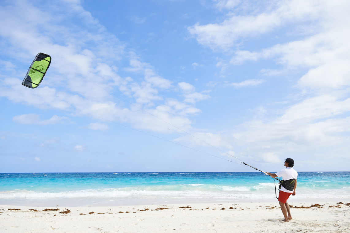 Man flying a kite in the blue clouded sky