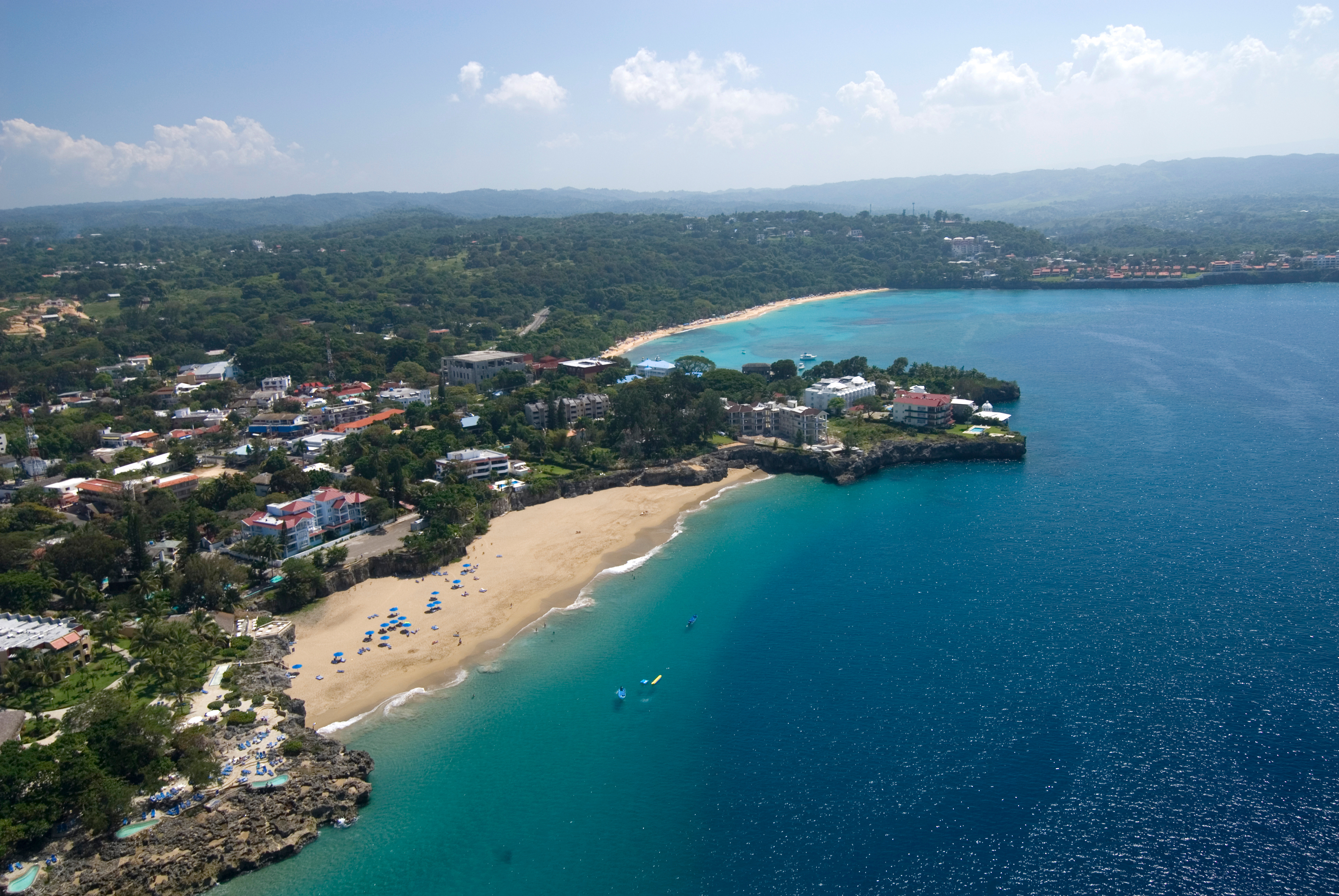 Aerial view of a small tropical beach backed by hotels and a small town