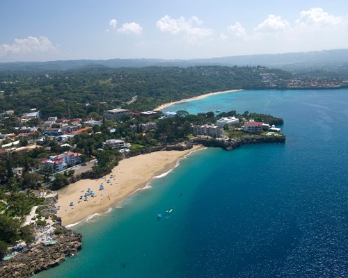 Aerial view of a small tropical beach backed by hotels and a small town
