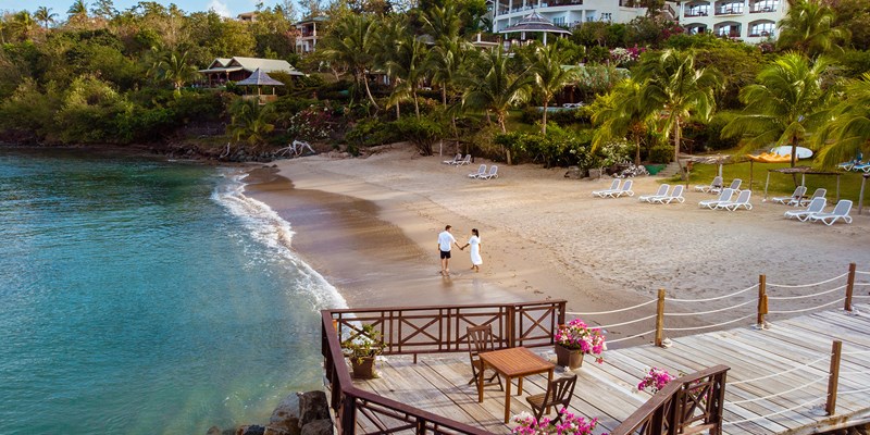 Couple on holiday walking along a beach at the tropical island of St Lucia