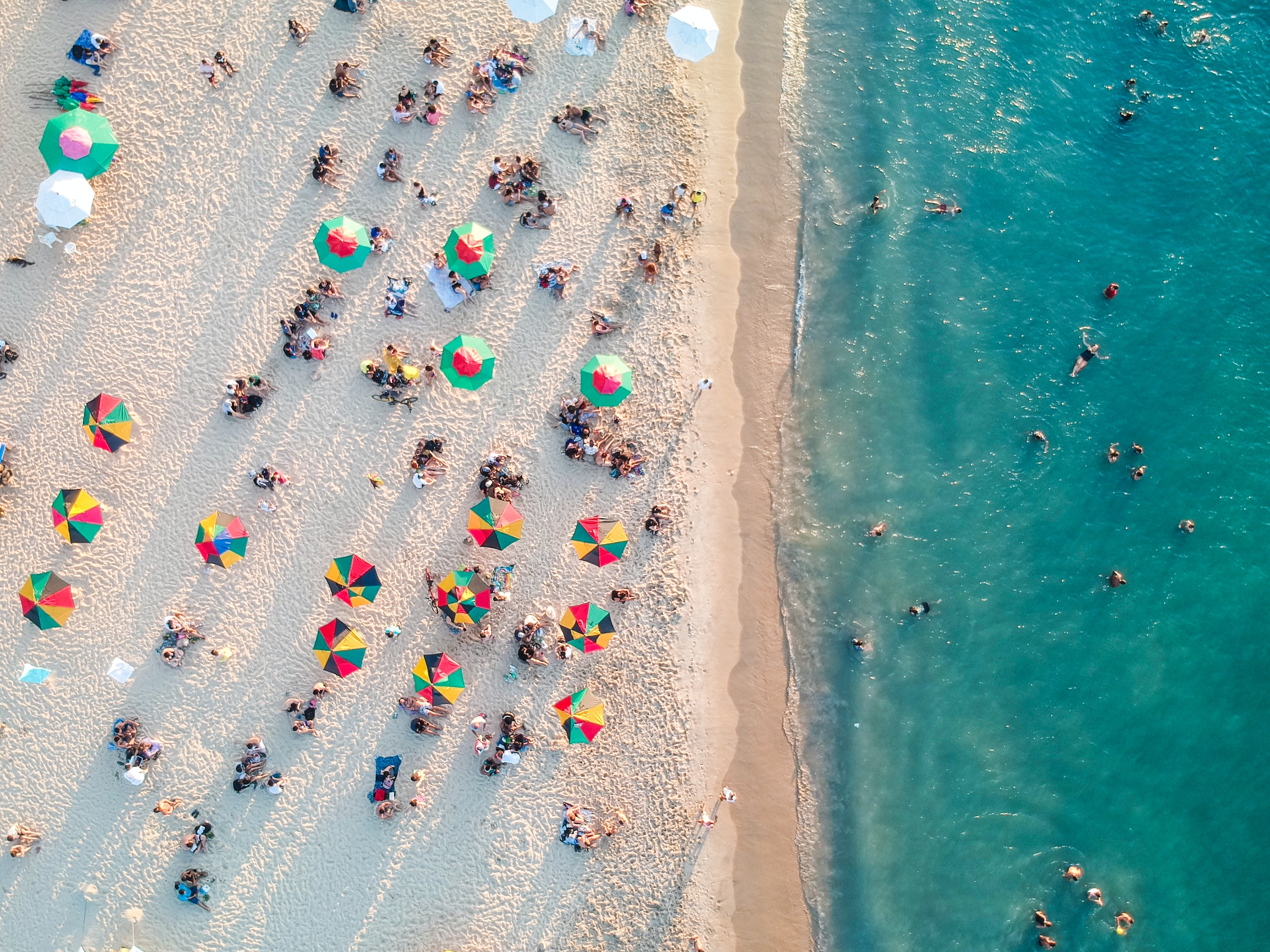 People enjoying a vast beach with azure waters