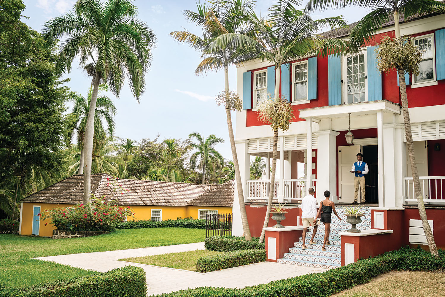 Large red house with blue shutters surrounded by tropical gardens