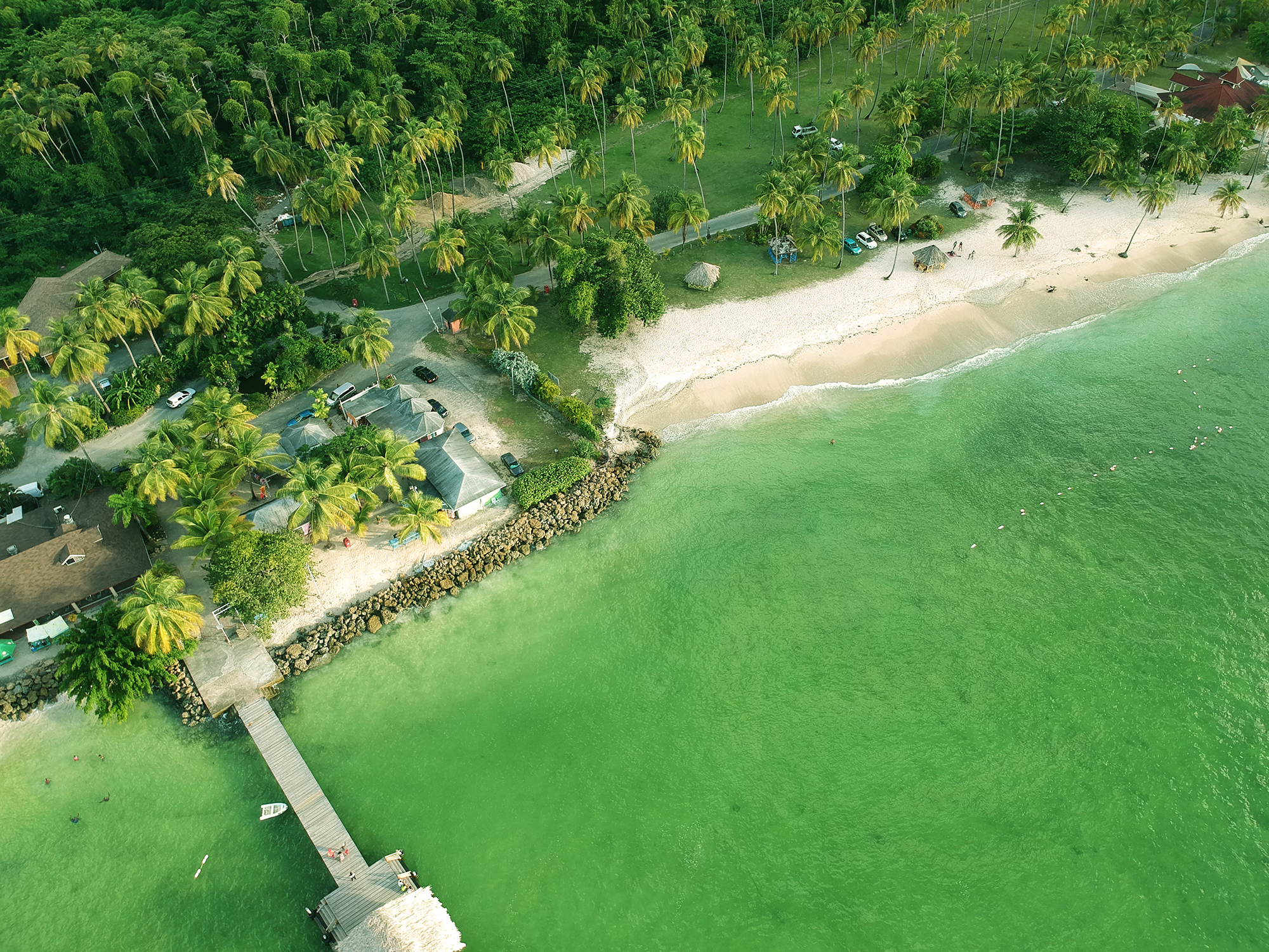Aerial view of a tropical beach with a pier over clear green water