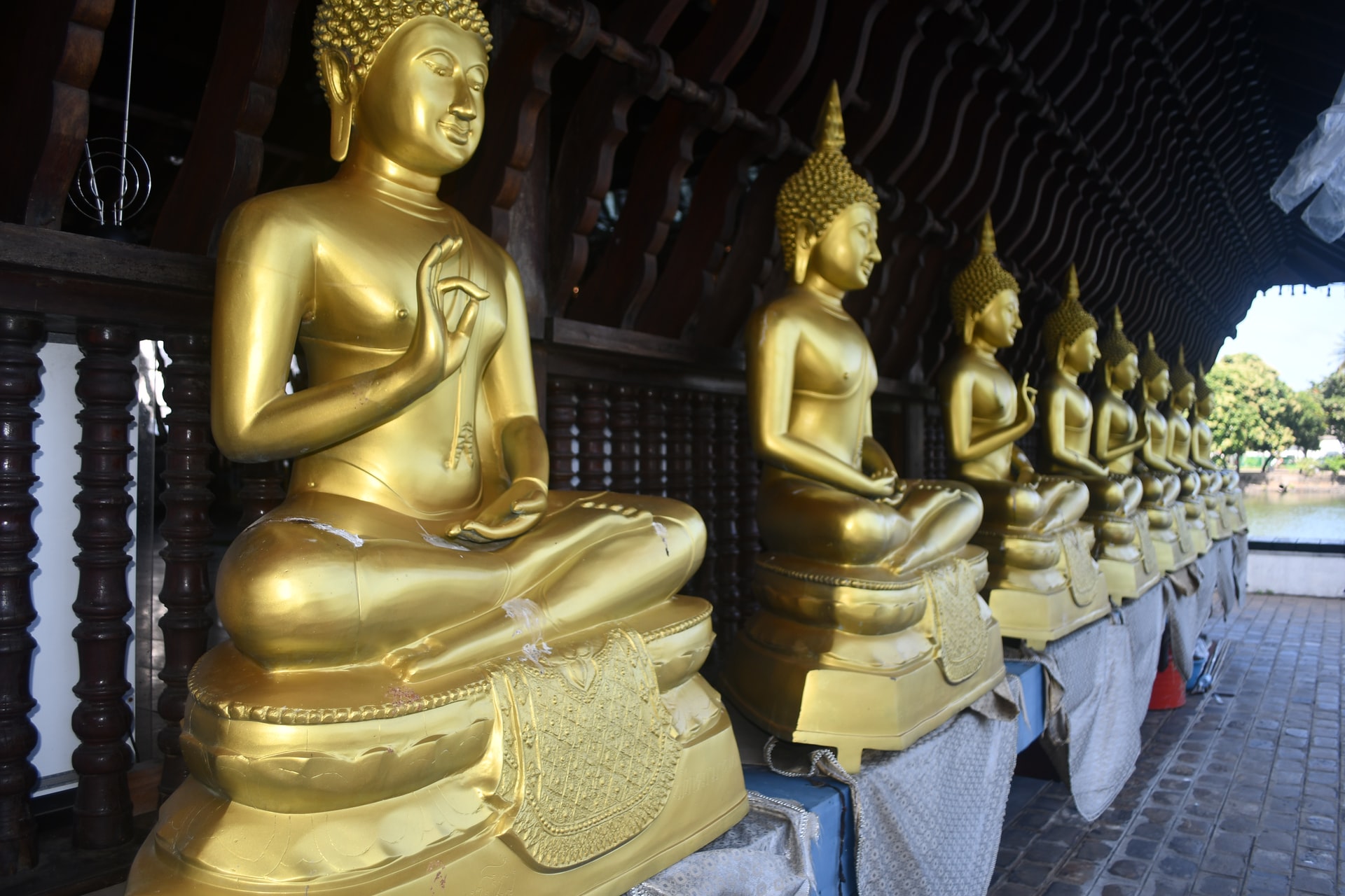 Three large gold Buddha statues outside a building covered in fairy lights