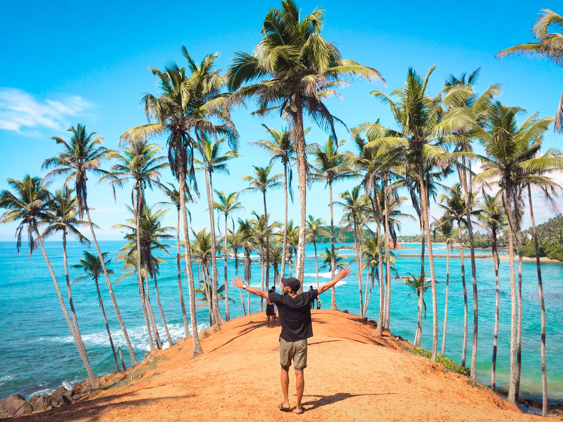 Men standing on Mirissa Beach among coconut palms