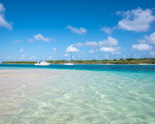 2 yachts in clear blue sea docked by tropical island