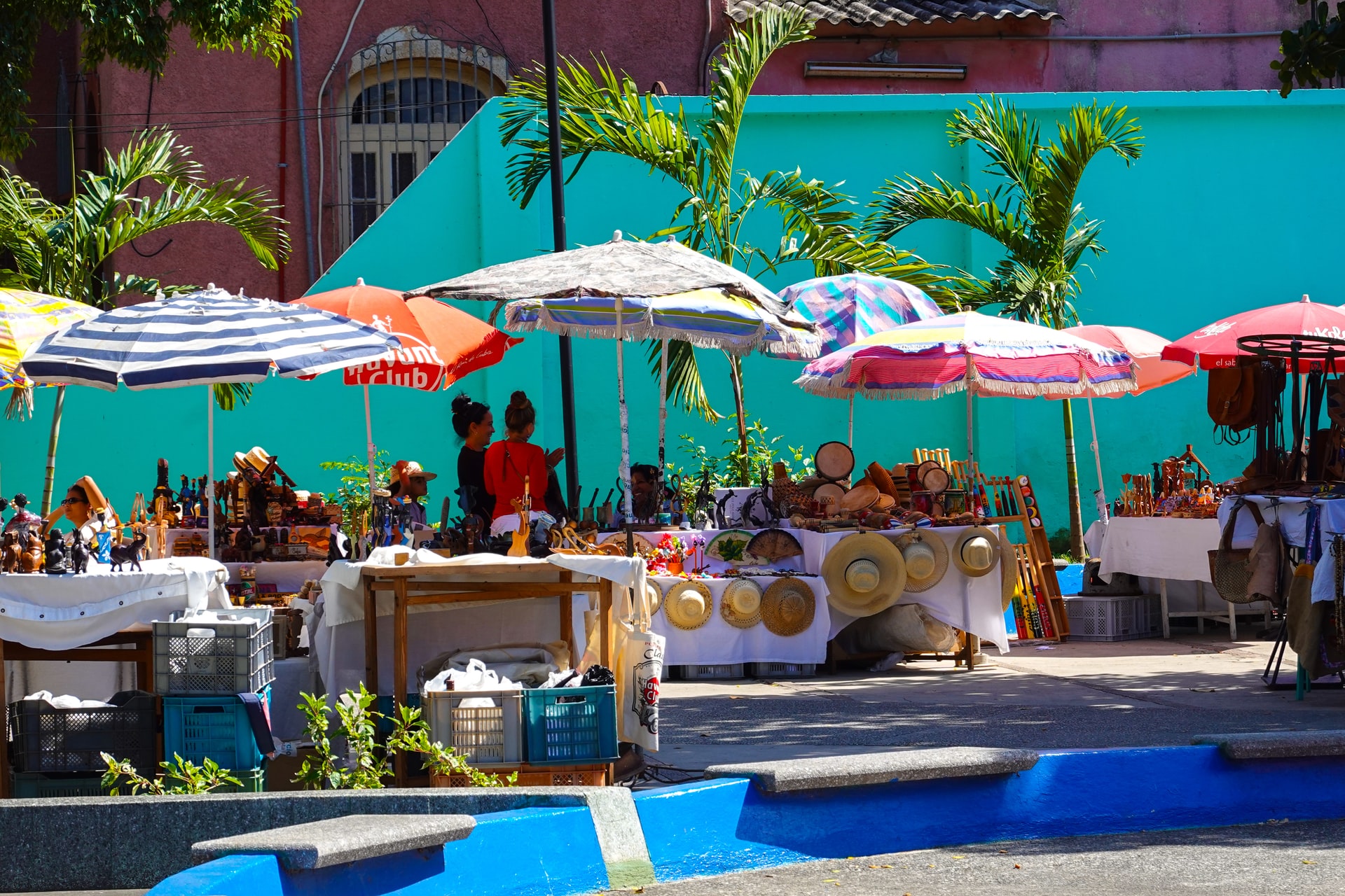 Two women browsing stalls at a street market in Cuba