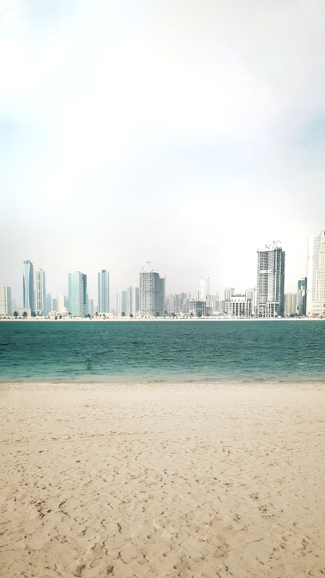 A wide beach with white sands backed by tall buildings