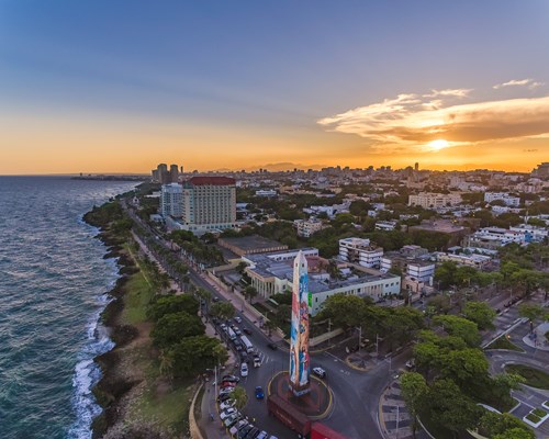 A large obelisk on the coast of a city on a tropical island