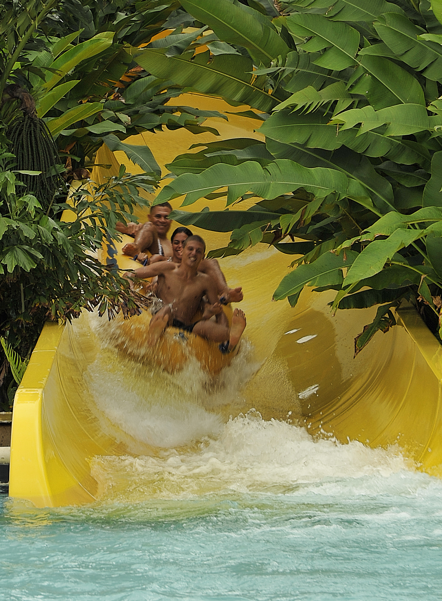 3 teens going down a large yellow waterslide