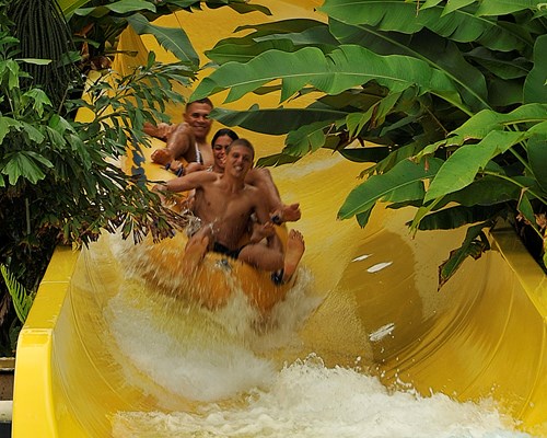 3 teens going down a large yellow waterslide