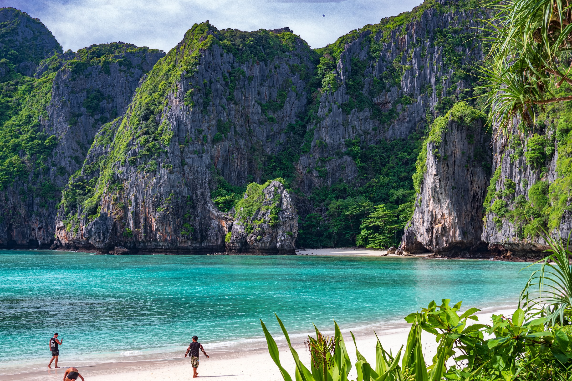 secret holiday-makers sunbathing spot on white sandy beach with azure sea and verdant rocky outcrops