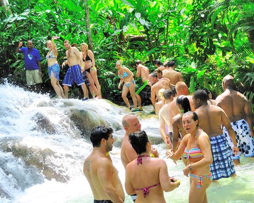 Group of people lined up as they walk through a shallow river