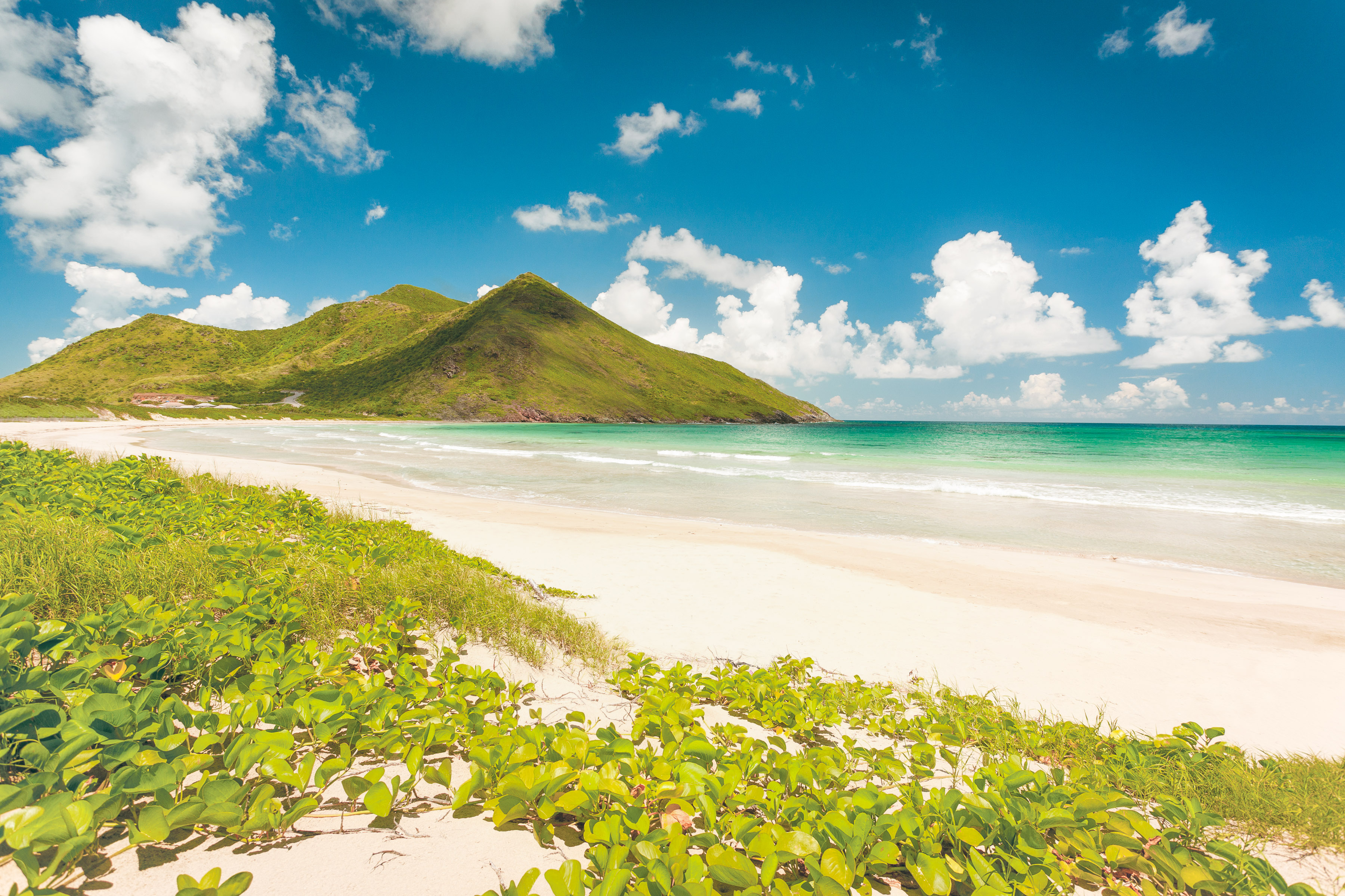View of small mountainous island from a tropical white sand beach