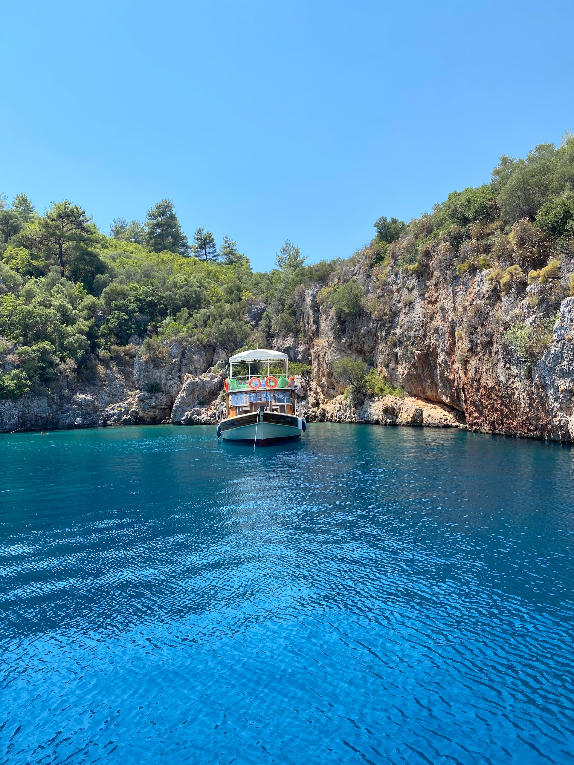 A boat sailing on a body of water backed by cliffs