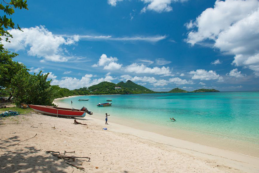 Kids playing on a tropical beach next to a docked small red motorboat 