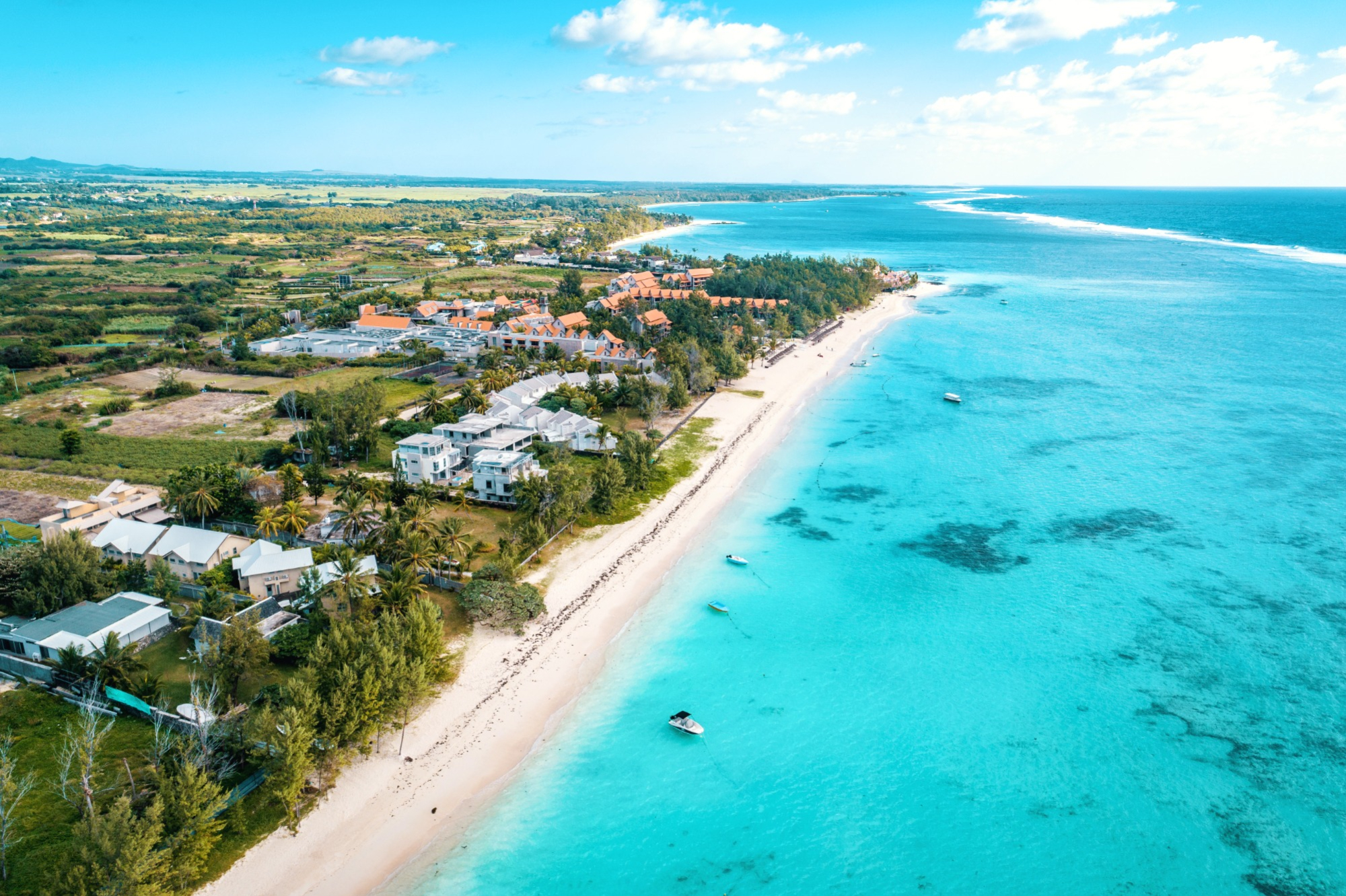 Aerial view of stretch of narrow white sand beach and tropical clear blue sea