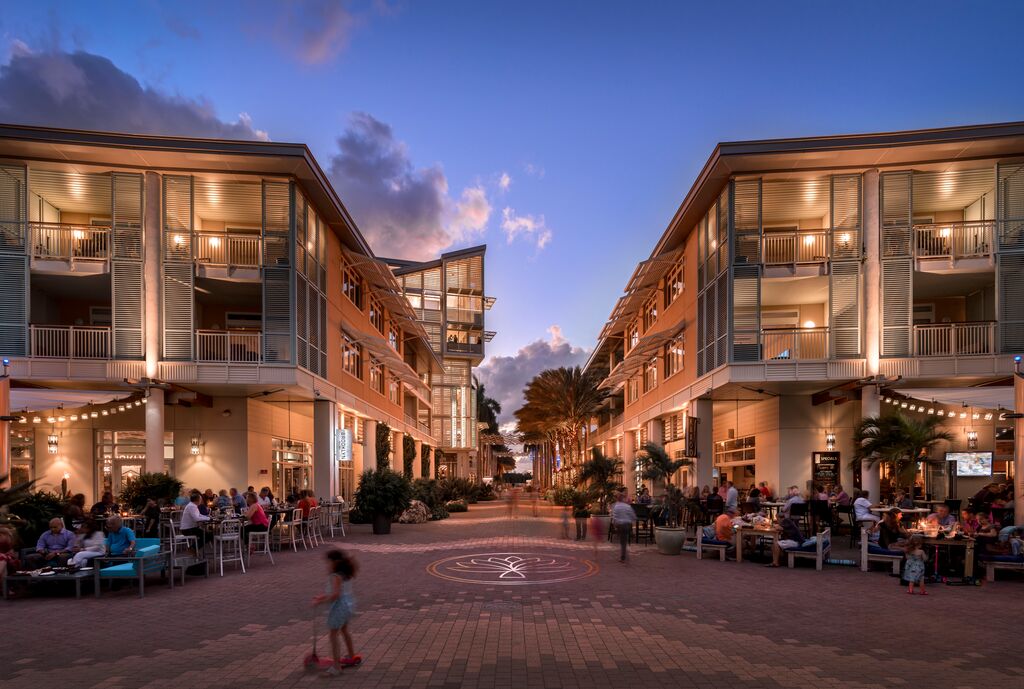 Buildings and shops lit up at night with sun setting in the background 