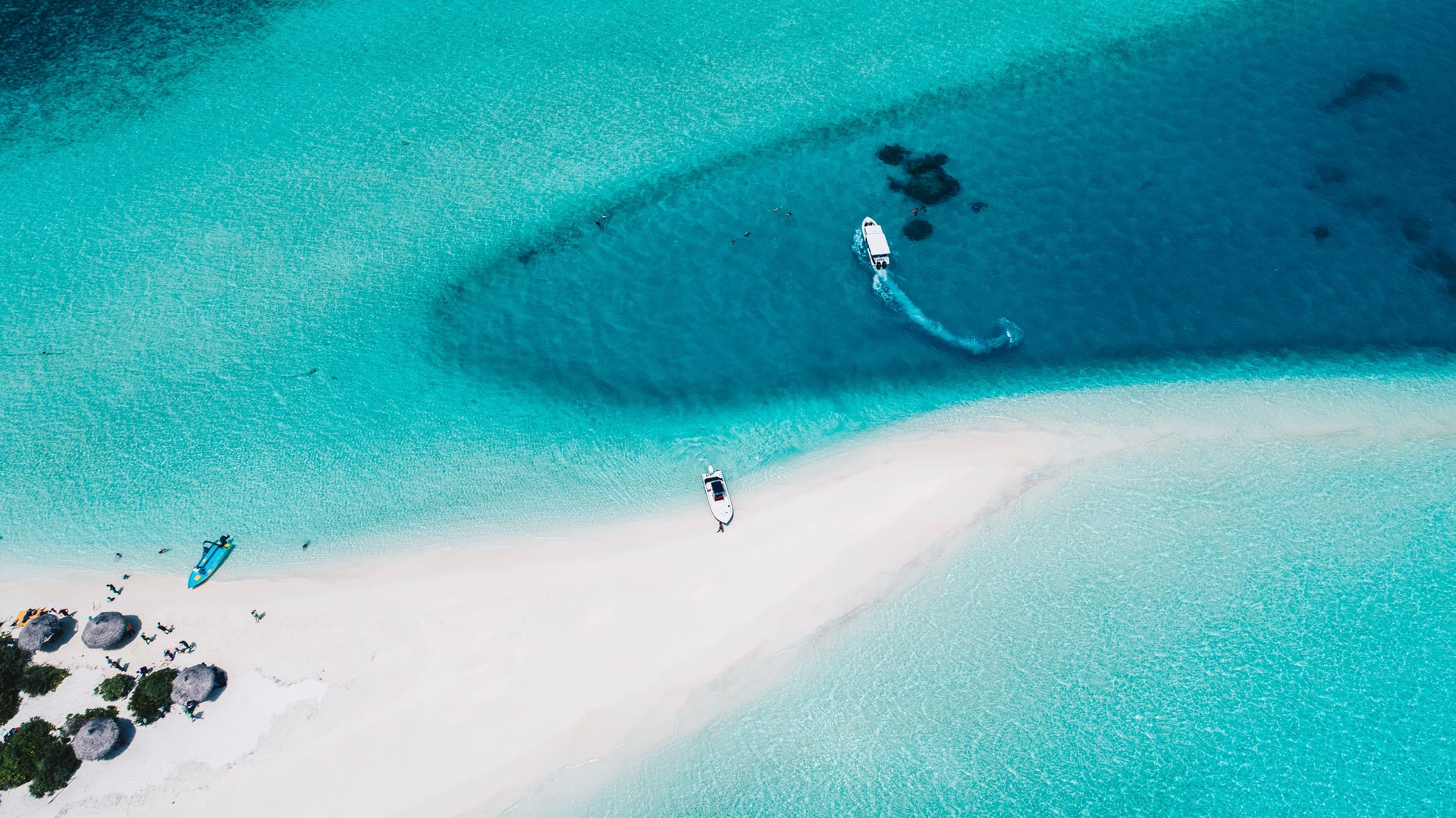 Aerial view of speedboat turning around near a small white-sand beach