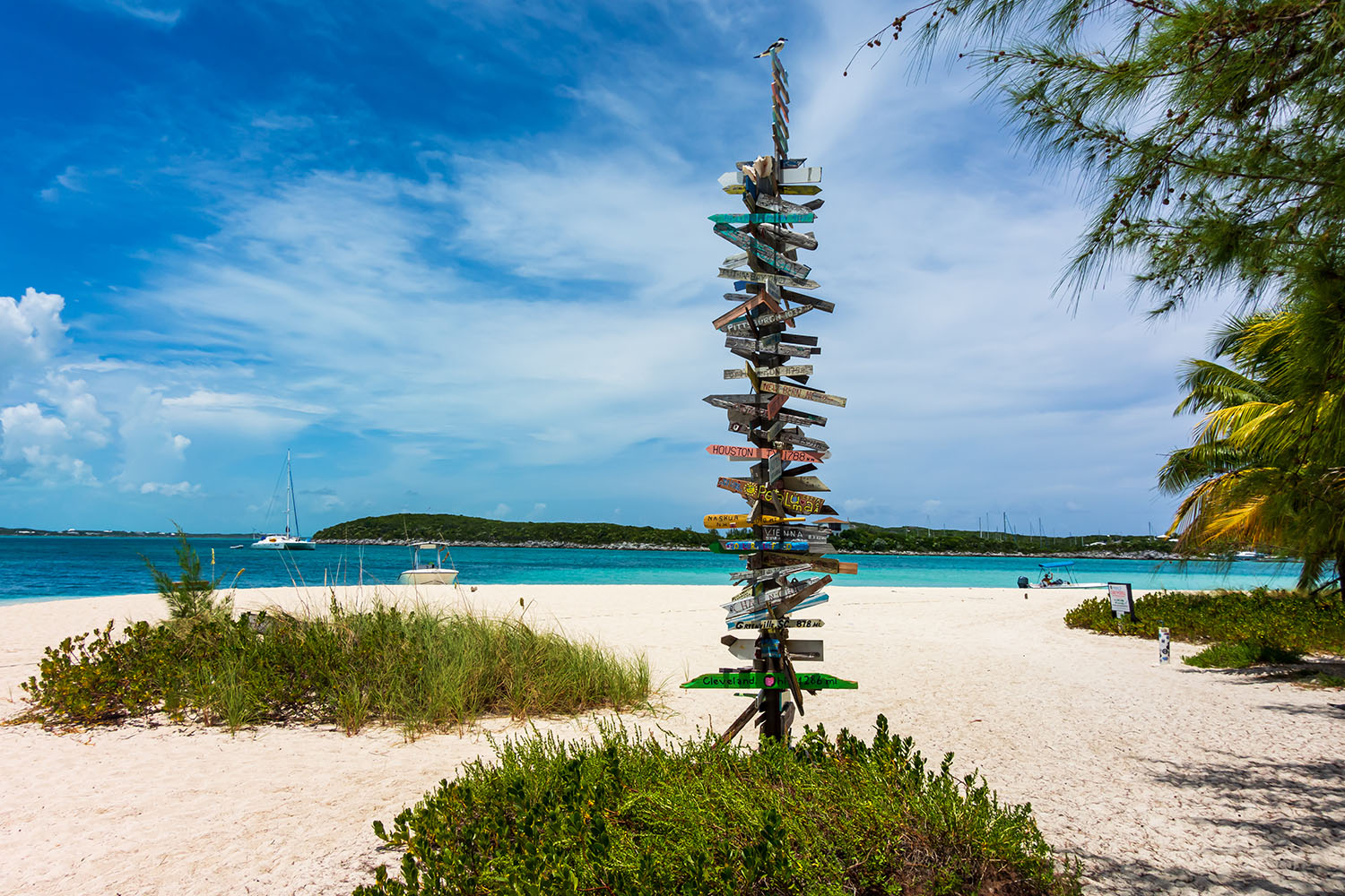 Tall signpost with lots of direction signs on a tropical beach