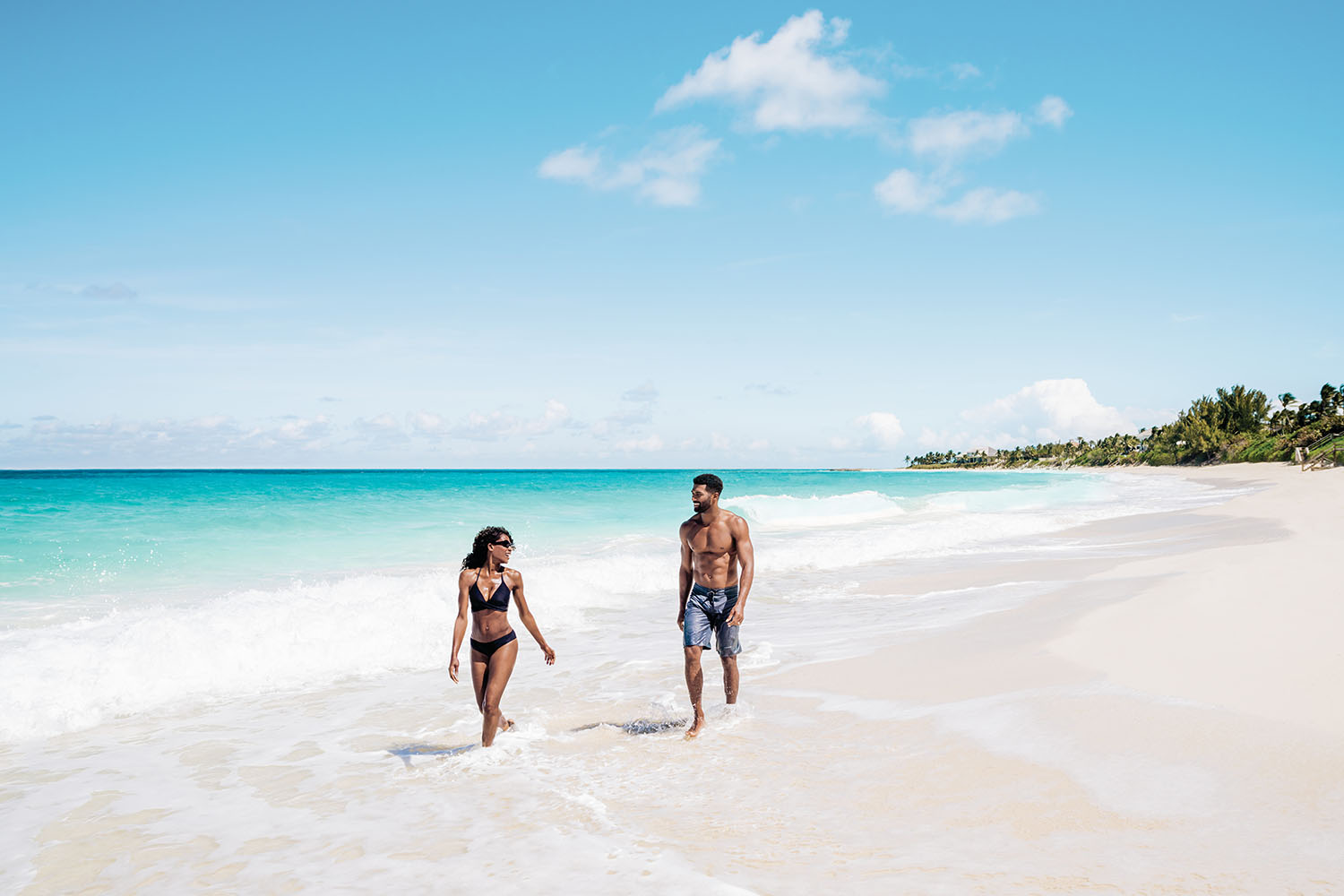 Couple walking along white sand tropical beach