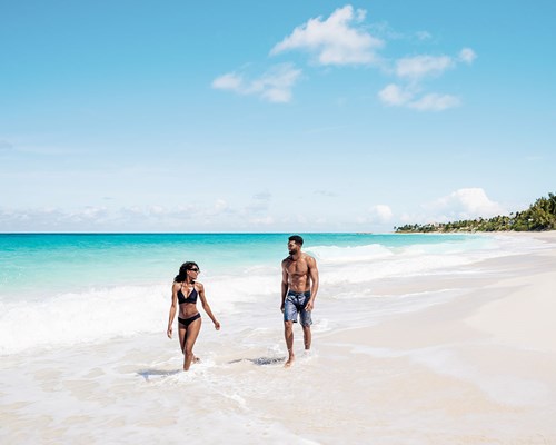 Couple walking along white sand tropical beach