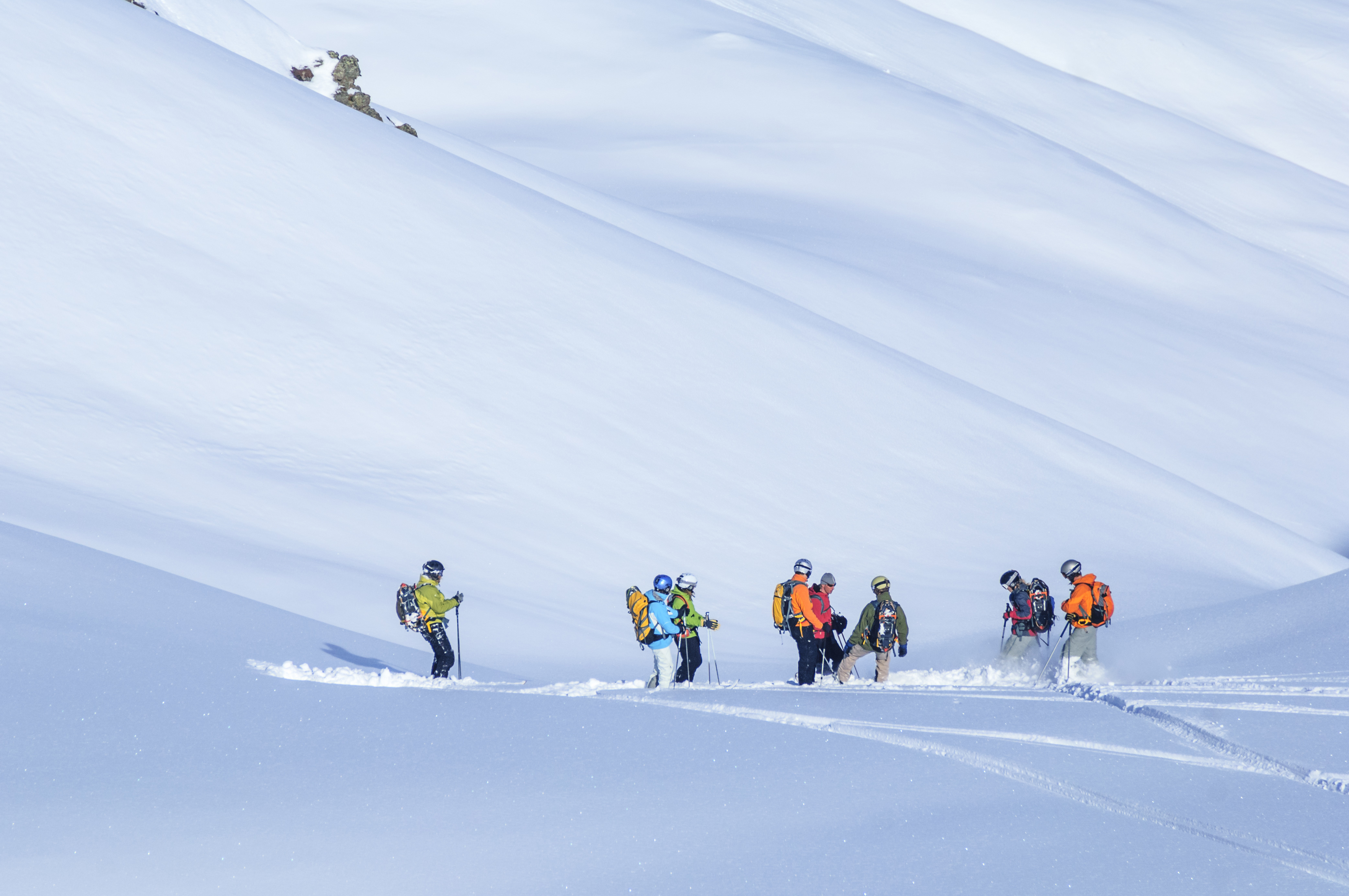 group of skiers & snowboarders in deep powder skiing off piste
