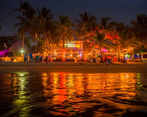 A row of beach bars lit up at night