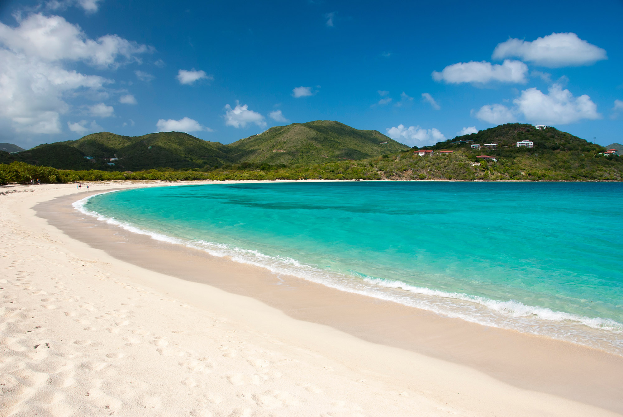 Empty white sand beach curving round the coast with forest covered mountains in the background - Smugglers Cove, Tortola