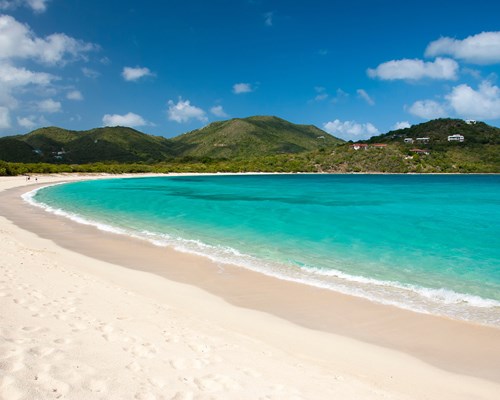 Empty white sand beach curving round the coast with forest covered mountains in the background - Smugglers Cove, Tortola