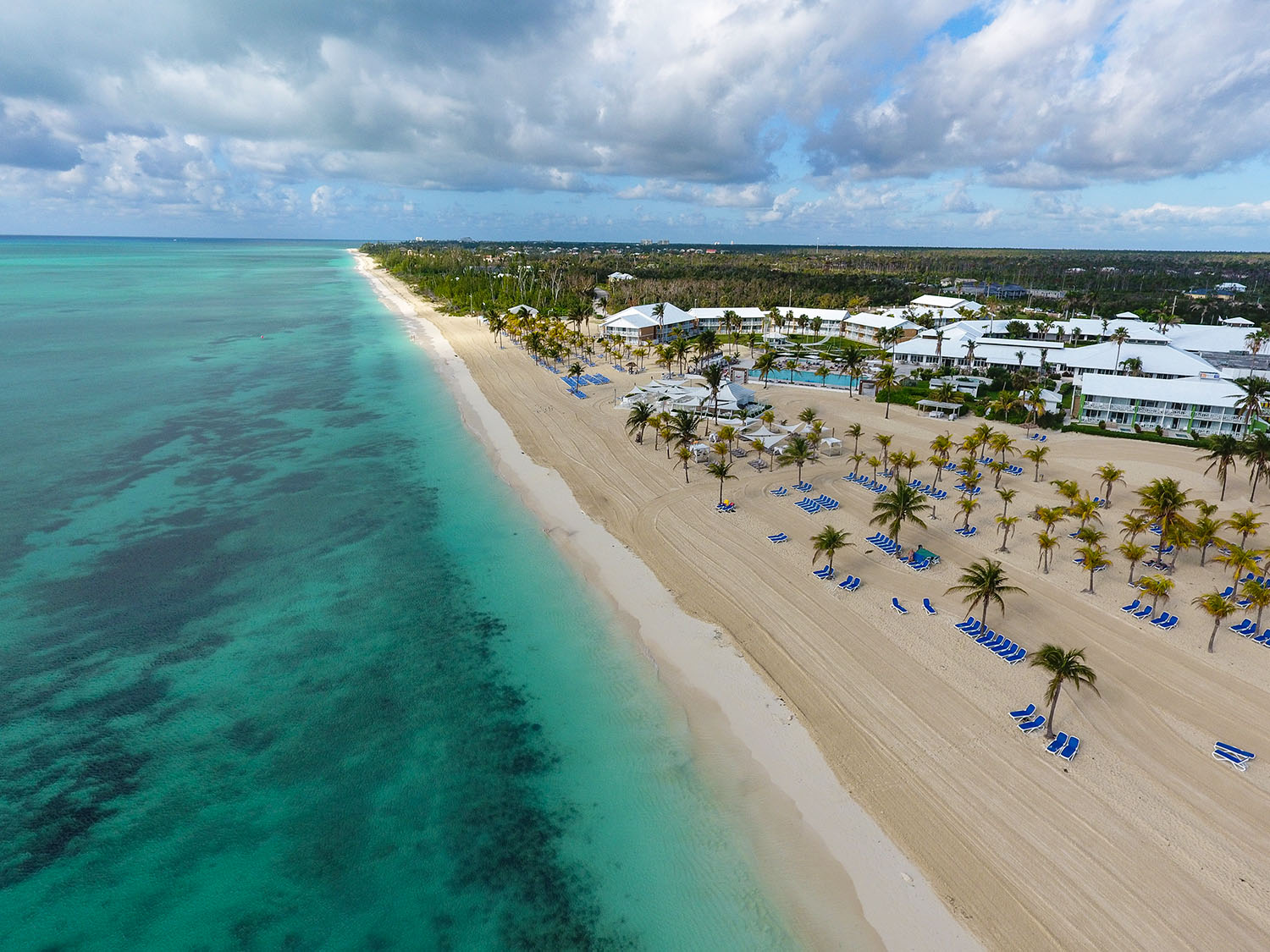 Stretch of white sand beach next to a large hotel resort in the Bahamas