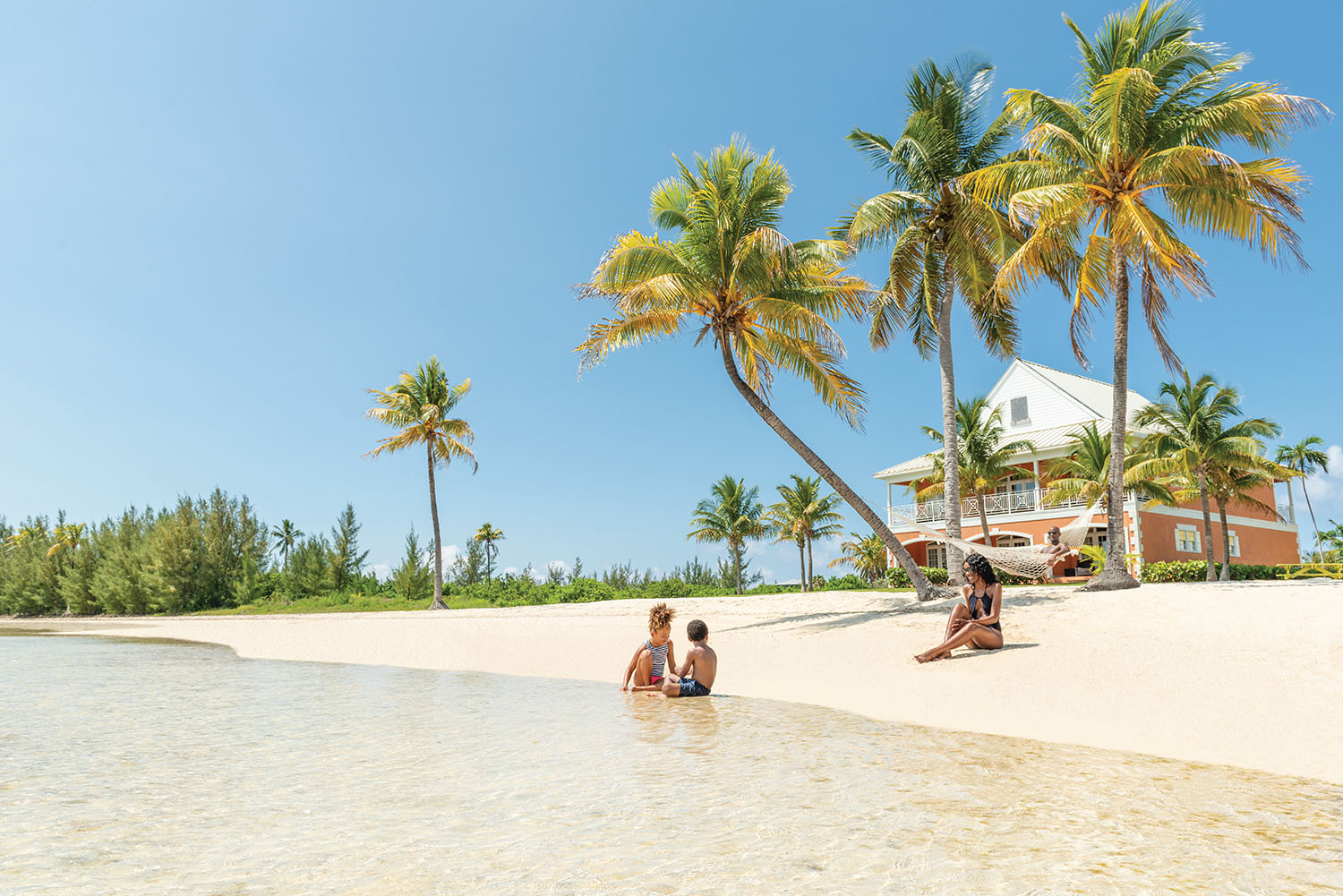 Family playing on golden beach by a single orange beach villa 
