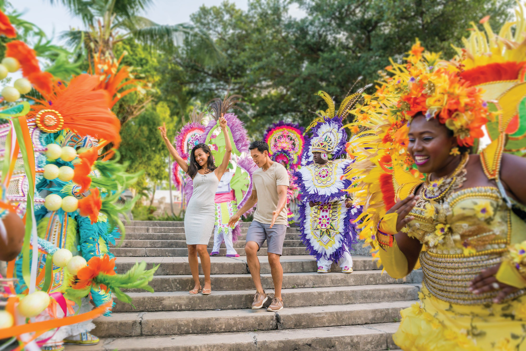 Couple standing among carnival dancers dressed in colourful costumes