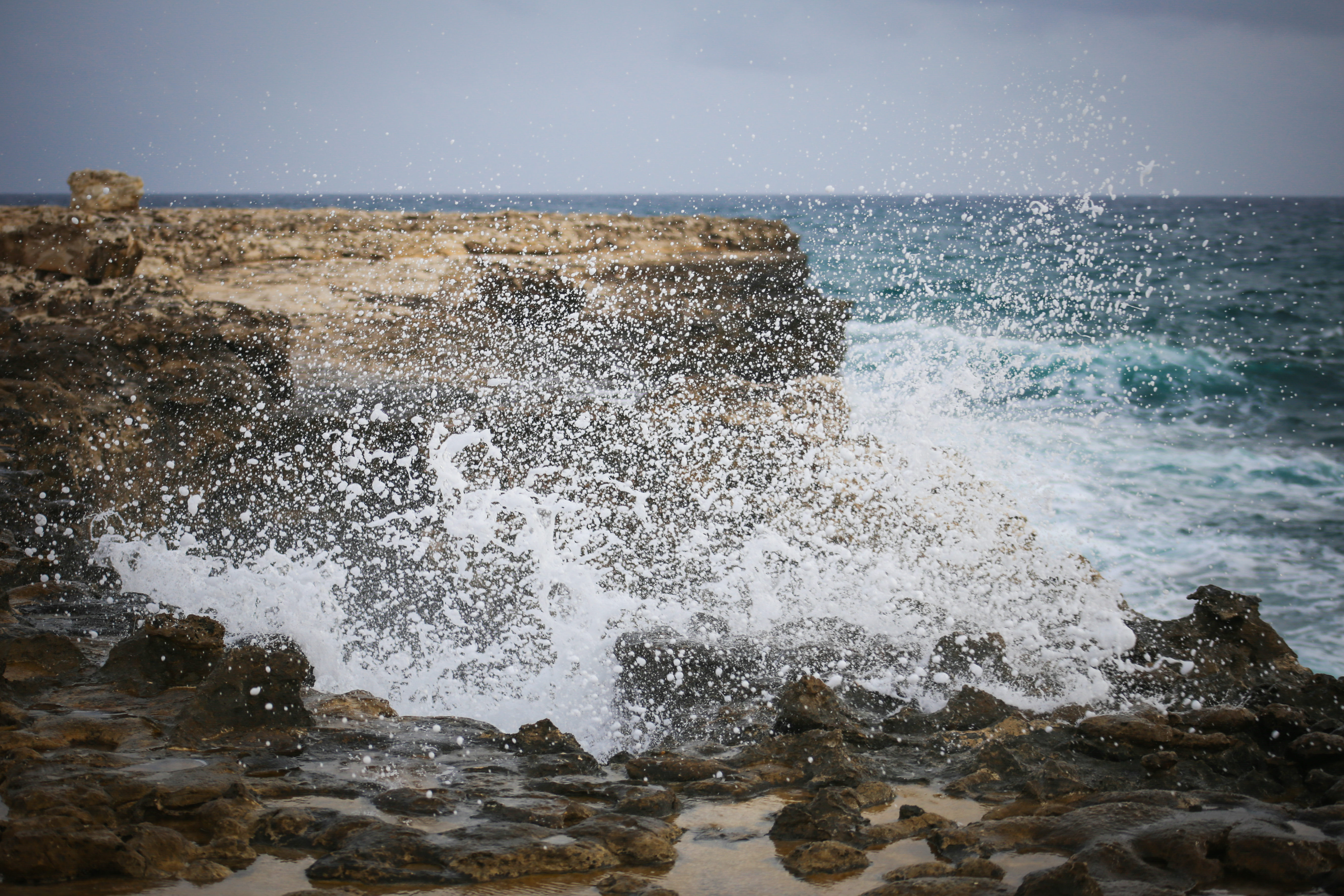 Waves crashing into a cliff at Devil's Bridge