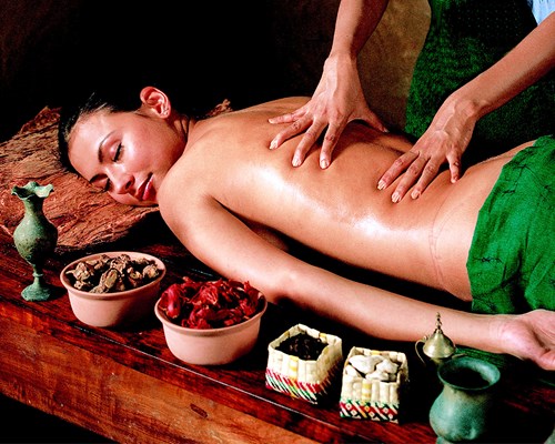 Woman laying on a wooden table getting a back massage