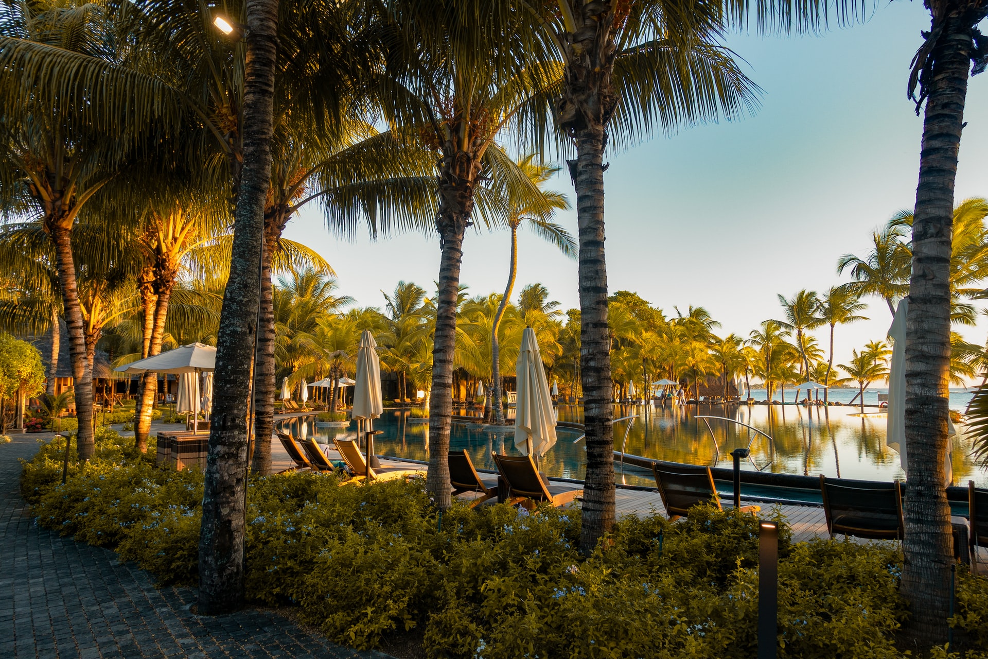 Empty sunbeds and parasols laid out around a pool in a beach resort as the sunsets 