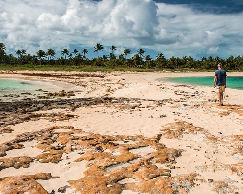 Man walking on a beach between two tropical coves